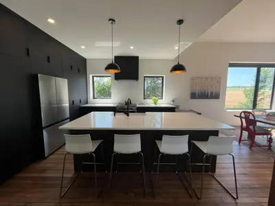 a kitchen with a large island with white chairs at Duncan in Kimberley
