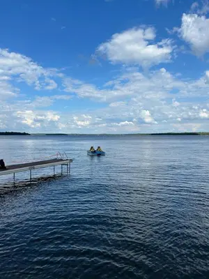 two people in a boat on the water near a dock at Water Front Cottage - Balsam Lake in Victoria Road