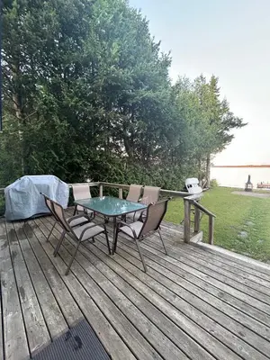 a patio with a table and chairs on a wooden deck at Water Front Cottage - Balsam Lake in Victoria Road