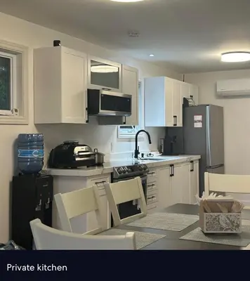 a kitchen with white cabinets and a table and chairs at Water Front Cottage - Balsam Lake in Victoria Road