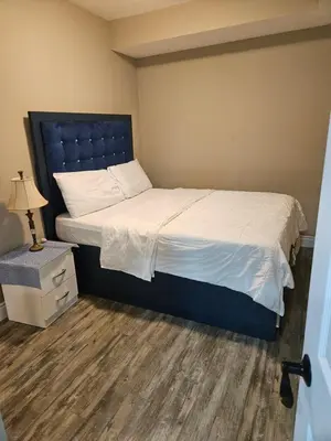 a bedroom with a large bed with a blue headboard at Beautiful 3 bedrooms, 2 bathrooms, 4 beds sleep 8, basement close to Falls in Niagara Falls