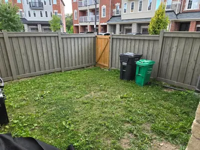 a yard with two trash cans and a fence at One Bed basement Room in Brampton