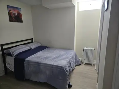 a bedroom with a bed with a blue blanket at One Bed basement Room in Brampton