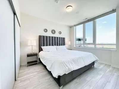 a bedroom with a large bed and a large window at The Panorama Penthouse - 180 Views and Free Parking by Instant Suites in Toronto
