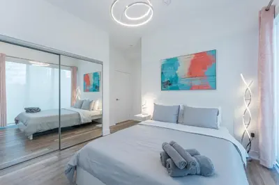a white bedroom with a large bed with towels on it at Shore Breeze in Toronto