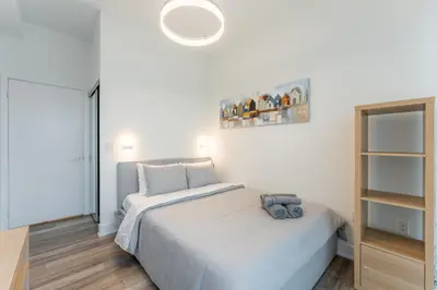a white bedroom with a bed and a mirror at Shore Breeze in Toronto