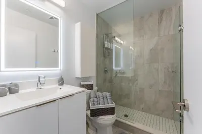 a bathroom with a shower and a toilet and a sink at Shore Breeze in Toronto