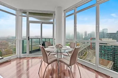 a dining room with a table and chairs and large windows at Downtown Condo with Picturesque View in Toronto