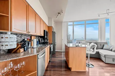 a kitchen with wooden cabinets and a living room at Downtown Condo with Picturesque View in Toronto