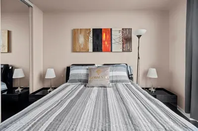 a bedroom with a bed with two lamps and a painting at Downtown Condo with Picturesque View in Toronto