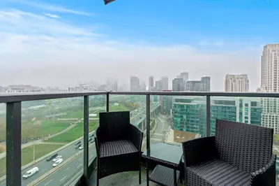 two chairs on a balcony with a view of a city at Downtown Condo with Picturesque View in Toronto