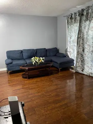 a living room with a blue couch and a table at 2-3 Bedroom Friends or Family Dwelling in Brampton