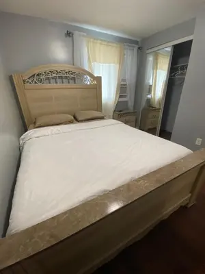 a bedroom with a large bed with white sheets at 2-3 Bedroom Friends or Family Dwelling in Brampton