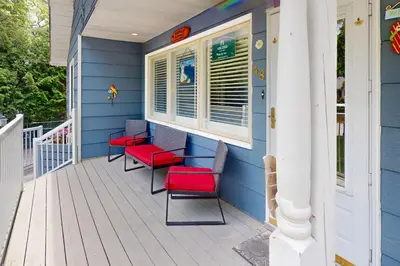 a porch with red chairs and a blue house at Wavy Daze Master in Wasaga Beach