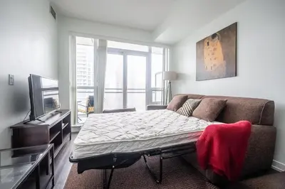 a bed in a room with a couch and a tv at Modern 1 Bedroom Dunfield Ave Apartment in Toronto
