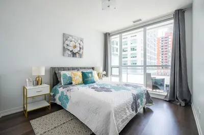 a bedroom with a bed and a large window at Modern Apartments 2BR 2BA Lillian St with Balcony in Toronto