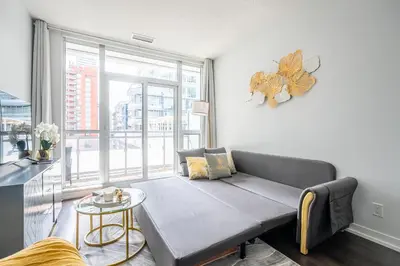 a living room with a couch and a large window at Modern Apartments 2BR 2BA Lillian St with Balcony in Toronto