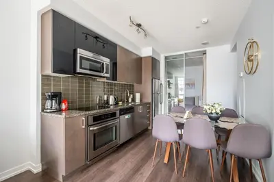 a kitchen with a table with purple chairs and a dining room at Modern Apartments 2BR 2BA Lillian St with Balcony in Toronto