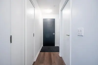 a hallway with white walls and a black door at Modern Apartments 2BR 2BA Lillian St with Balcony in Toronto