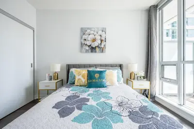 a bedroom with a king sized bed with a floral bedspread at Modern Apartments 2BR 2BA Lillian St with Balcony in Toronto