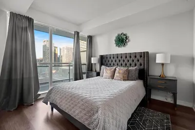 a bedroom with a large bed and a large window at Modern 1Bd & Den Condo with Balcony Lillian St in Toronto