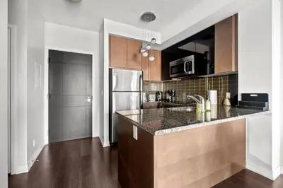 a kitchen with a counter and a refrigerator at Modern 1Bd & Den Condo with Balcony Lillian St in Toronto