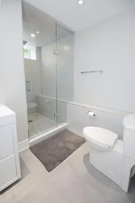 a white bathroom with a toilet and a shower at Stylish 1BR in Queen West in Toronto