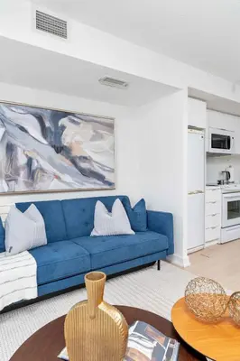a living room with a blue couch and a table at Charming Condo w Private Patio in Quiet Capreol in Toronto