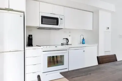 a white kitchen with white appliances and a microwave at Charming Condo w Private Patio in Quiet Capreol in Toronto