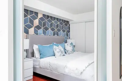 a bedroom with a white bed with blue pillows at Charming Condo w Private Patio in Quiet Capreol in Toronto