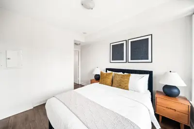 a white bedroom with a large bed with yellow pillows at Modern 2BR in TO Near Yorkville & the Village in Toronto