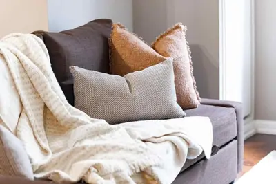 a blanket sitting on a couch with pillows at Modern Oasis Stylish 2BR Condo Near Attractions in Toronto