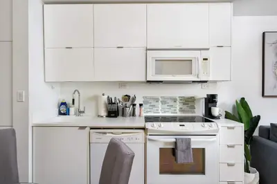 a white kitchen with a stove and a microwave at Modern Waterfront Comfort Condo with City Views in Toronto