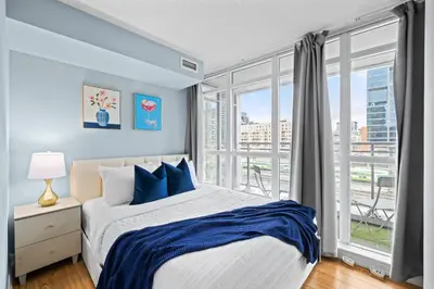 a bedroom with a bed and a large window at Spacious 3BR Condo w Patio & Skyline Views in Toronto