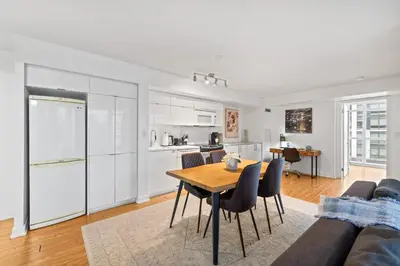 a kitchen and living room with a table and chairs at Spacious 3BR Condo w Patio & Skyline Views in Toronto
