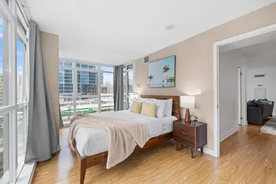 a bedroom with a bed and a large window at Spacious 3BR Condo w Patio & Skyline Views in Toronto