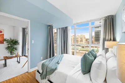 a bedroom with a white bed and a large window at Spacious 3BR Condo w Patio & Skyline Views in Toronto