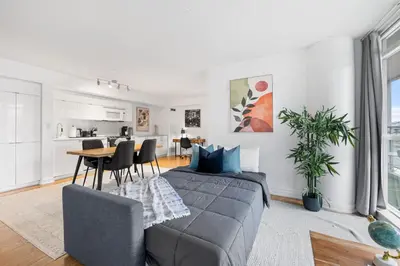 a bedroom with a bed and a table and a kitchen at Spacious 3BR Condo w Patio & Skyline Views in Toronto