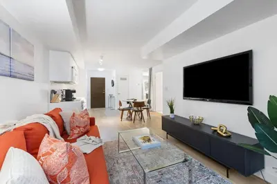 a living room with a orange couch and a flat screen tv at Modern & Stylish Comfort in the Heart of Toronto in Toronto