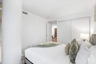 a white bedroom with a large white bed with pillows at Modern & Stylish Comfort in the Heart of Toronto in Toronto