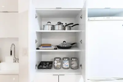 a kitchen with white shelves with pots and pans at Modern & Stylish Comfort in the Heart of Toronto in Toronto