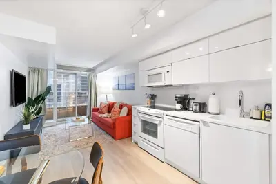 a kitchen with white appliances and a dining room at Modern & Stylish Comfort in the Heart of Toronto in Toronto