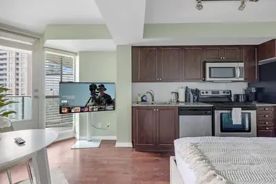 a living room with a kitchen with a flat screen tv at Cozy Waterfront Studio plus Parking by the Bentway in Toronto