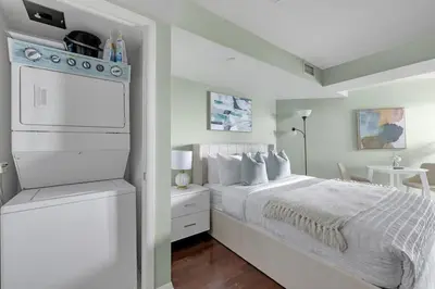 a white bedroom with a bed and a stove at Cozy Waterfront Studio plus Parking by the Bentway in Toronto