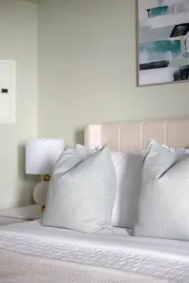 a bed with white pillows and a picture on the wall at Cozy Waterfront Studio plus Parking by the Bentway in Toronto