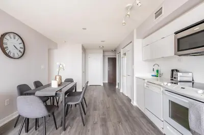 a kitchen and dining room with a table and chairs and a clock at Corner 2 Bedroom 2 Bathroom Condo Balcony Iceboat Terrace Downtown Toronto in Toronto