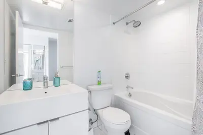 a white bathroom with a toilet and a tub and a sink at Corner 2 Bedroom 2 Bathroom Condo Balcony Iceboat Terrace Downtown Toronto in Toronto