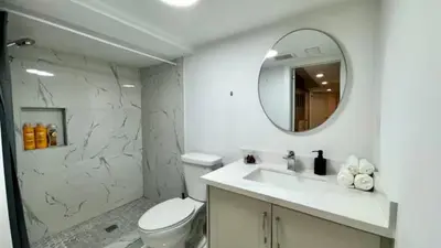 a white bathroom with a toilet and a mirror at Spacious and Luxurious 2BR Suite with Huge Windows in Mississauga
