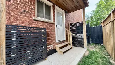 a front door of a brick house with a wooden gate at Spacious and Luxurious 2BR Suite with Huge Windows in Mississauga