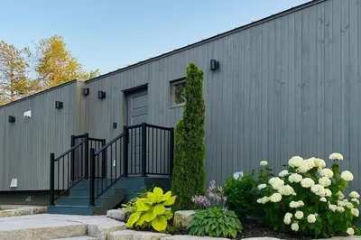 a gray building with a door and some flowers at Stoney Lake Cottage with Private Dock by Leavetown Vacations in Crowes Landing